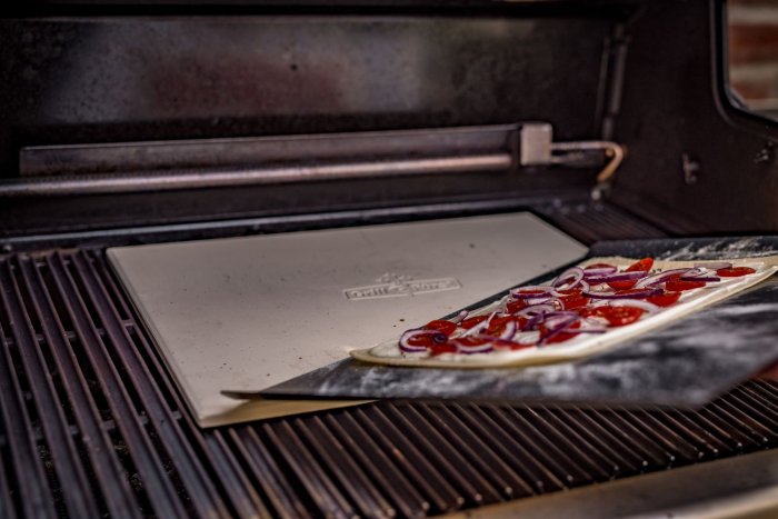 Die Pizza mit einem Blech auf den vorgeheizten Stein schieben.